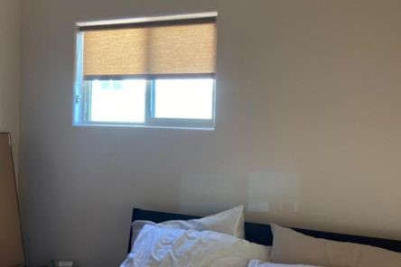 Berkeley bedroom window with custom roller sheer shades partially drawn, letting in soft natural light above a cozy bed.